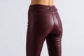 Beautiful slim booty girl. Leather burgundy skinny pants with pockets. Close up view on and legs.