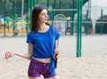 Beautiful slim european woman posing on the beach playing badminton