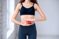 Beautiful slim girl in dark sportwear holding red apple in the hands near her attractive belly. Healthy lifestyle, diet Royalty Free Stock Photo