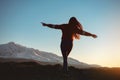 Slim girl with raised arms against sunset mountains Royalty Free Stock Photo
