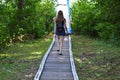 A beautiful slim girl woman with brown long hair and legs in short shorts goes down the stairs in a park in nature with green