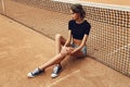 Beautiful slim tennis girl with dark hair wears sports clothes, posing on tennis court