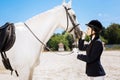 Beautiful slim woman loving equestrianism looking at white horse