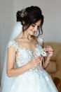 Beautiful slim young caucasian bride holding a flower boutonniere. morning of the bride