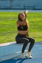 Beautiful slim young runner woman, happy, enjoying drinking and hydrating herself with her mouth open with a flask of water or an Royalty Free Stock Photo