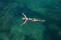 Beautiful slim young woman in a bikini swims on her back in the turquoise sea water Royalty Free Stock Photo