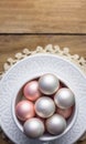 Beautiful small Christmas tree ornaments white pink pearl red balls in vintage ceramic cup on sauces lace napkin. Aged wood Royalty Free Stock Photo