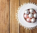 Beautiful small Christmas tree ornaments white pink pearl red balls in vintage ceramic cup on sauces lace napkin. Weathered wood Royalty Free Stock Photo