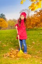 Beautiful small girl works with yellow rake