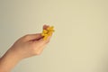 Small original yellow flower kept in the hand of a child on a light background