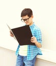 Beautiful smart teenager boy in glasses looking or reading book