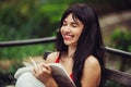 Beautiful smart woman reading a book and laughing in the green park outdoors Royalty Free Stock Photo