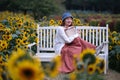 smile Asian young woman sit on bench surrounded by sunflowers Royalty Free Stock Photo