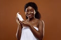 Beautiful African Woman Wrapped In Towel Holding Bottle With Moisturising Body Lotion Royalty Free Stock Photo