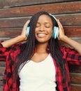 Beautiful smiling african woman with headphones enjoying listens music in city Royalty Free Stock Photo