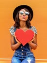Beautiful smiling african woman holding a red heart. Royalty Free Stock Photo