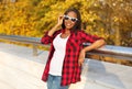 Beautiful smiling african woman wearing sunglasses, red checkered shirt in sunny autumn Royalty Free Stock Photo