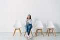 Beautiful smiling applicant talking on smartphone while sitting on chair