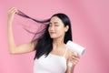 Beautiful Smiling Asian Girl With Black Long Straight Hair Using Hairdryer. Isolated on pink background Royalty Free Stock Photo