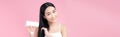 Beautiful Smiling Asian Girl With Black Long Straight Hair Using Hairdryer. Isolated on pink background Royalty Free Stock Photo