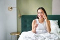 Beautiful smiling asian girl talking on mobile phone, lying in bed with pleased happy face, speaking to someone on Royalty Free Stock Photo