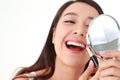 Beautiful smiling Asian woman applying lipstick to her mouth, holding a mirror to her face. Royalty Free Stock Photo