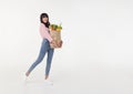 Beautiful smiling Asian woman holding shopping bag full of groceries and looking to copy space aside isolated on white background Royalty Free Stock Photo