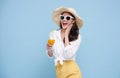 Beautiful smiling Asian woman in summer outfit with a glass of orange juice isolated on colorful blue background Royalty Free Stock Photo