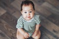 Beautiful smiling baby girl with big dark eyes dark hair sitting at floor and looking up at camera