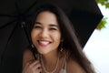 Beautiful smiling biracial woman or teen holding umbrella in rain Royalty Free Stock Photo