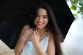 Beautiful smiling biracial woman or teen holding umbrella in rain