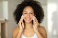 Beautiful smiling black woman cleans her skin with cotton pads and looks at the camera Royalty Free Stock Photo