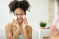 Beautiful smiling black woman cleans her skin with cotton pads and looks at the camera Royalty Free Stock Photo