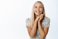 Beautiful smiling blond girl, looking with affection with something cute or adorable, standing in dress over white