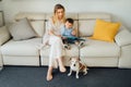 Beautiful smiling blond woman, 2 yers old boy and dog together in living room reading books. Royalty Free Stock Photo