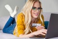 beautiful smiling blonde girl in eyeglasses holding credit card and using laptop Royalty Free Stock Photo