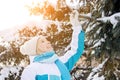 Beautiful smiling blonde girl shakes snow off a branch of a Christmas tree
