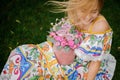 Beautiful smiling blonde girl sits on the lawn and holds round box with roses Royalty Free Stock Photo