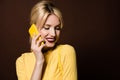 beautiful smiling blonde girl talking by yellow smartphone