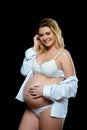 Beautiful smiling blonde pregnant woman in white clothes on a black background. Women`s health and happy pregnancy Royalty Free Stock Photo