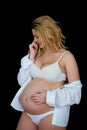 Beautiful smiling blonde pregnant woman in white clothes on a black background. Women`s health and happy pregnancy Royalty Free Stock Photo