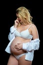 Beautiful smiling blonde pregnant woman in white clothes on a black background. Women`s health and happy pregnancy Royalty Free Stock Photo
