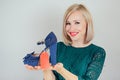 Beautiful smiling blonde woman shopaholic holding a stylish shoes with a red label tag , tab , tally in her hand Royalty Free Stock Photo