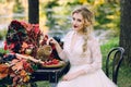 The bride with the owl. Beautiful smiling bride is sitting near the served wedding table with red autumn leaves Royalty Free Stock Photo