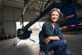 Beautiful smiling brunette airframe engineer sitting in the aviation garage Royalty Free Stock Photo