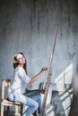 Beautiful smiling brunette female modern artist painting oilpaints in studio. Royalty Free Stock Photo