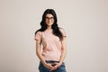 Beautiful smiling brunette girl wearing glasses in casual wear posing beside blank wall.