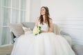 Beautiful smiling brunette woman bride in wedding dress with classical white roses bouquet in living room Royalty Free Stock Photo