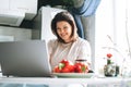 Beautiful smiling brunette young woman plus size body positive using laptop in kitchen at the home