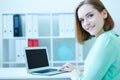 Beautiful smiling business woman sitting at office workplace half turn looking in camera portrait. Royalty Free Stock Photo